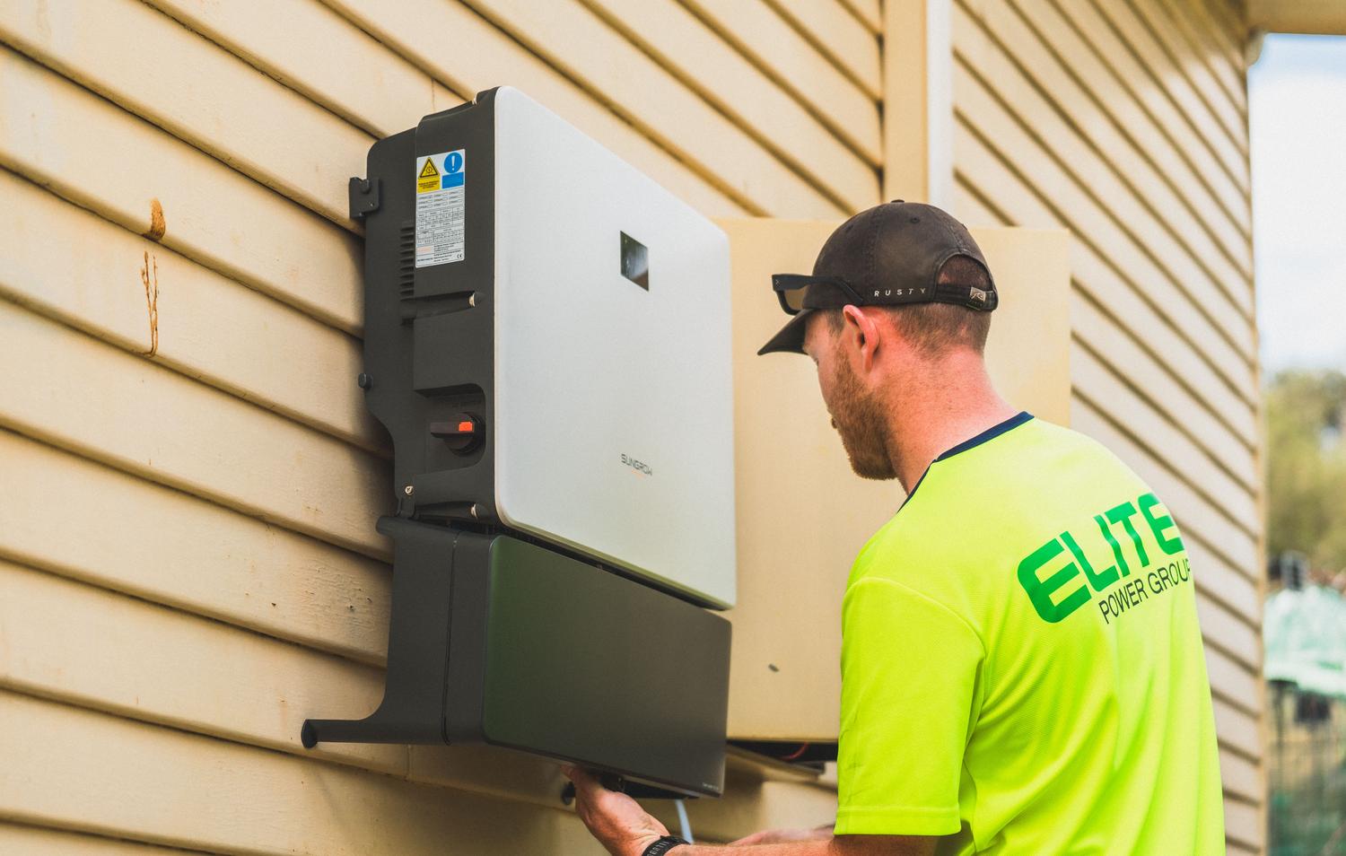 Técnico instalando un inversor solar, componente clave para la gestión de baterías distribuidas.