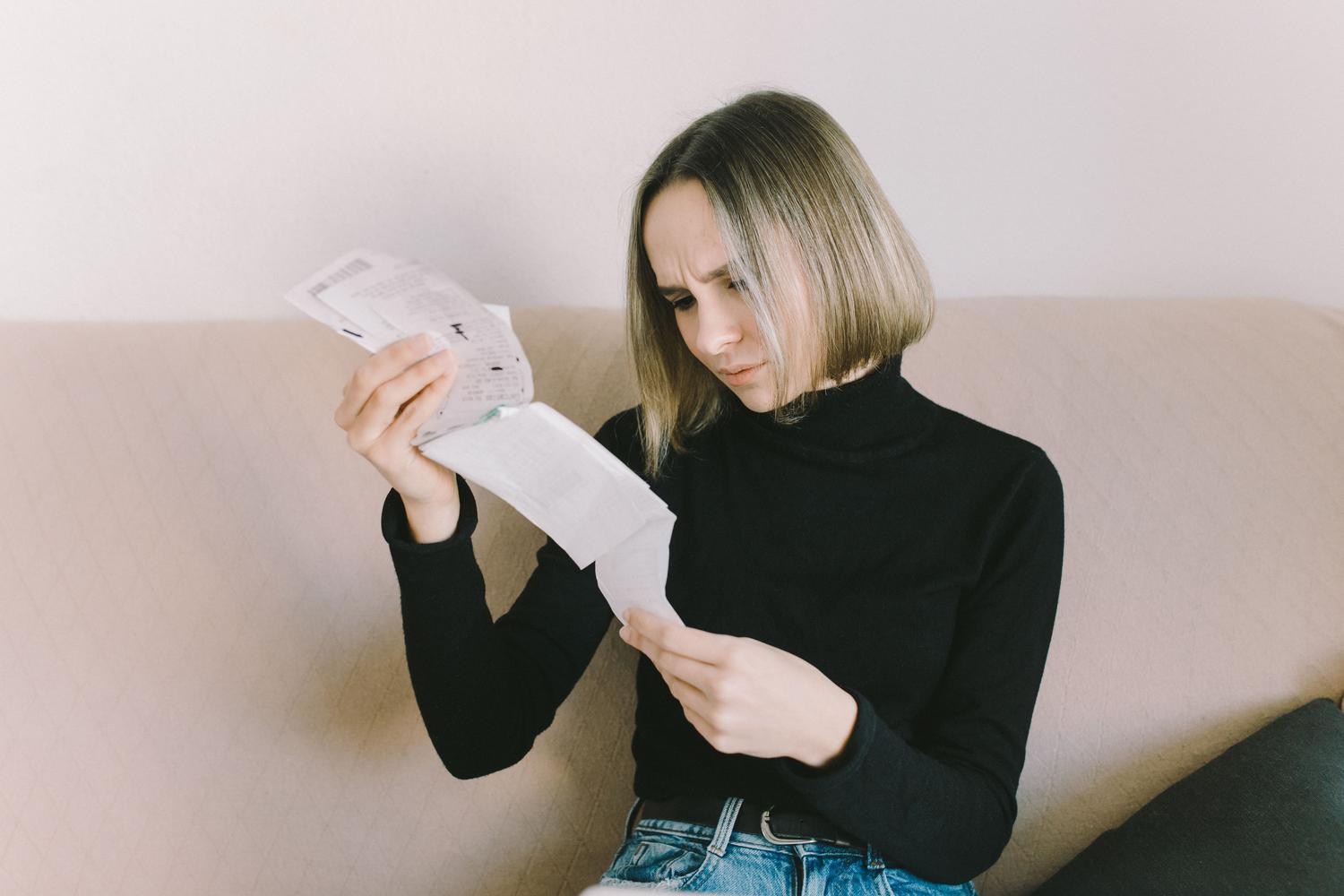 Mujer revisando con preocupación su factura de gas en el sofá