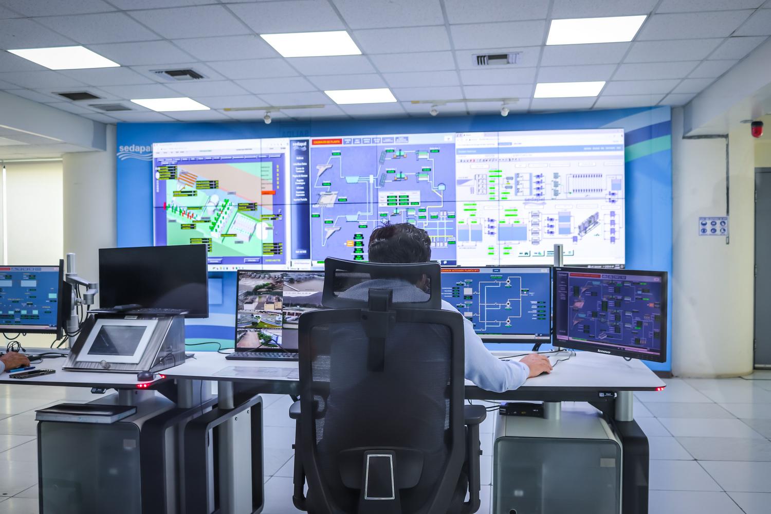 Operador en una sala de control moderna gestionando sistemas tecnológicos para la monitorización de emisiones