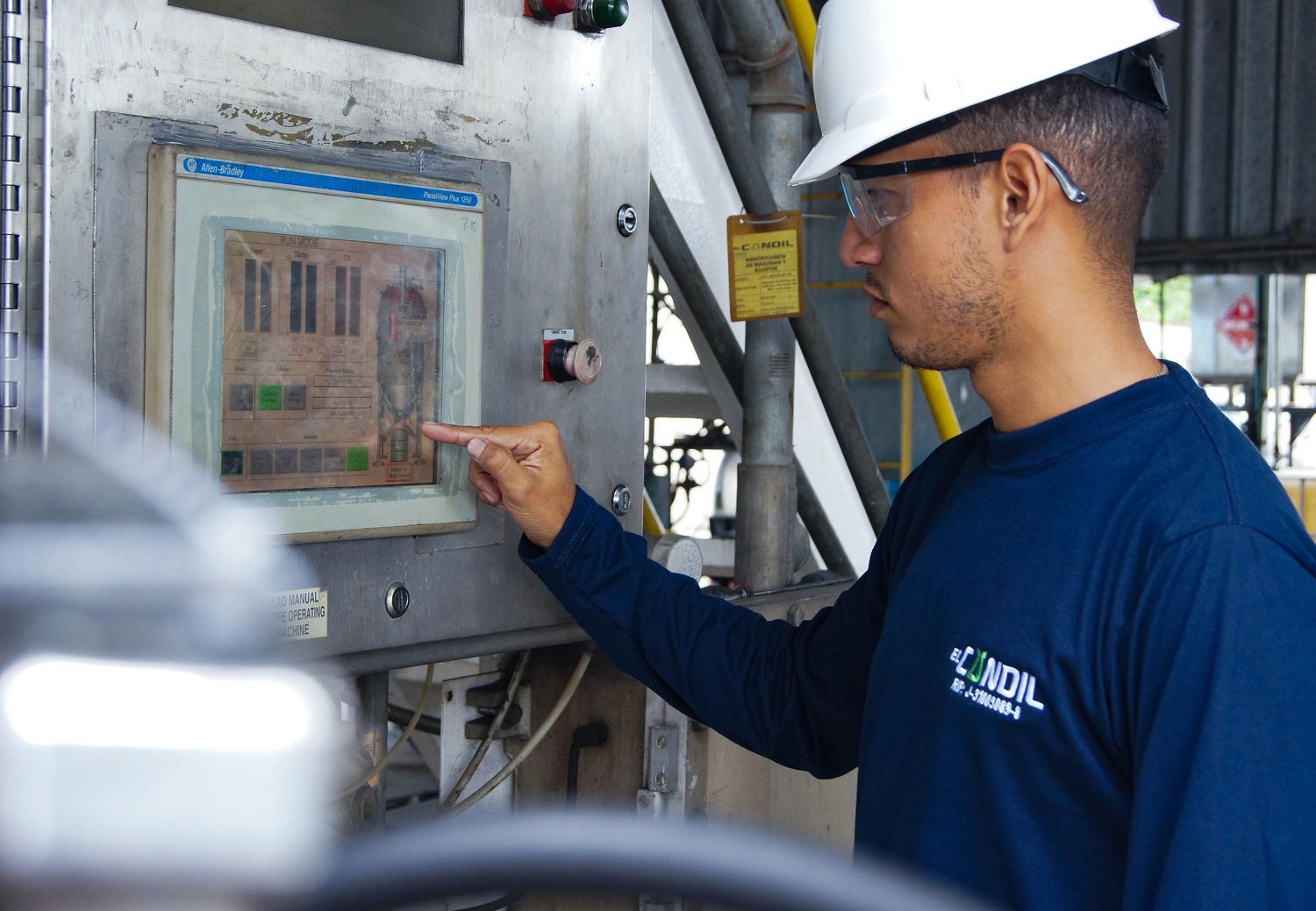 Ingeniero supervisando un panel de control en una instalación industrial para asegurar el cumplimiento normativo