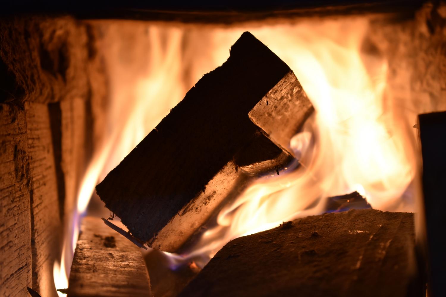 Leños ardiendo en una chimenea con llamas vibrantes, transmitiendo calor y confort en el hogar.