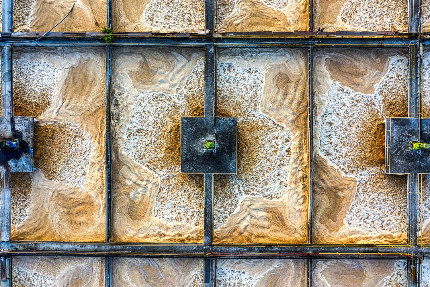 Detalle aéreo de los tanques de una depuradora, ilustrando los procesos de tratamiento biológico y anaerobio.
