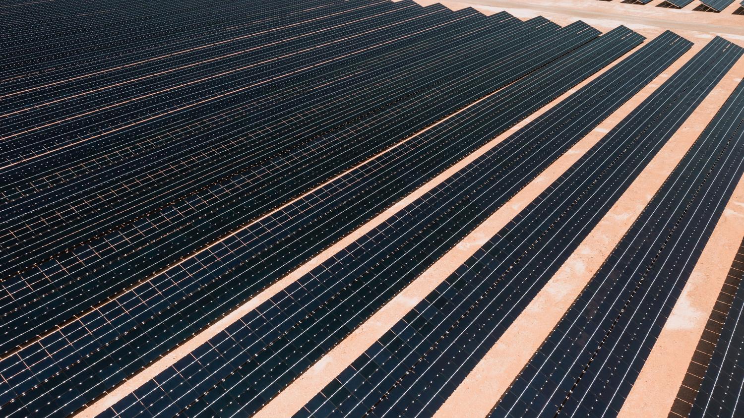 Parque solar masivo en un paisaje árido, evocando las grandes instalaciones del desierto de Atacama en Chile o el norte de México.
