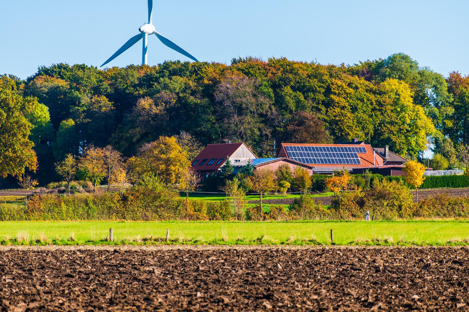 Granja sostenible que combina turbinas eólicas y paneles solares, ilustrando la agrivoltaica y los sistemas híbridos.