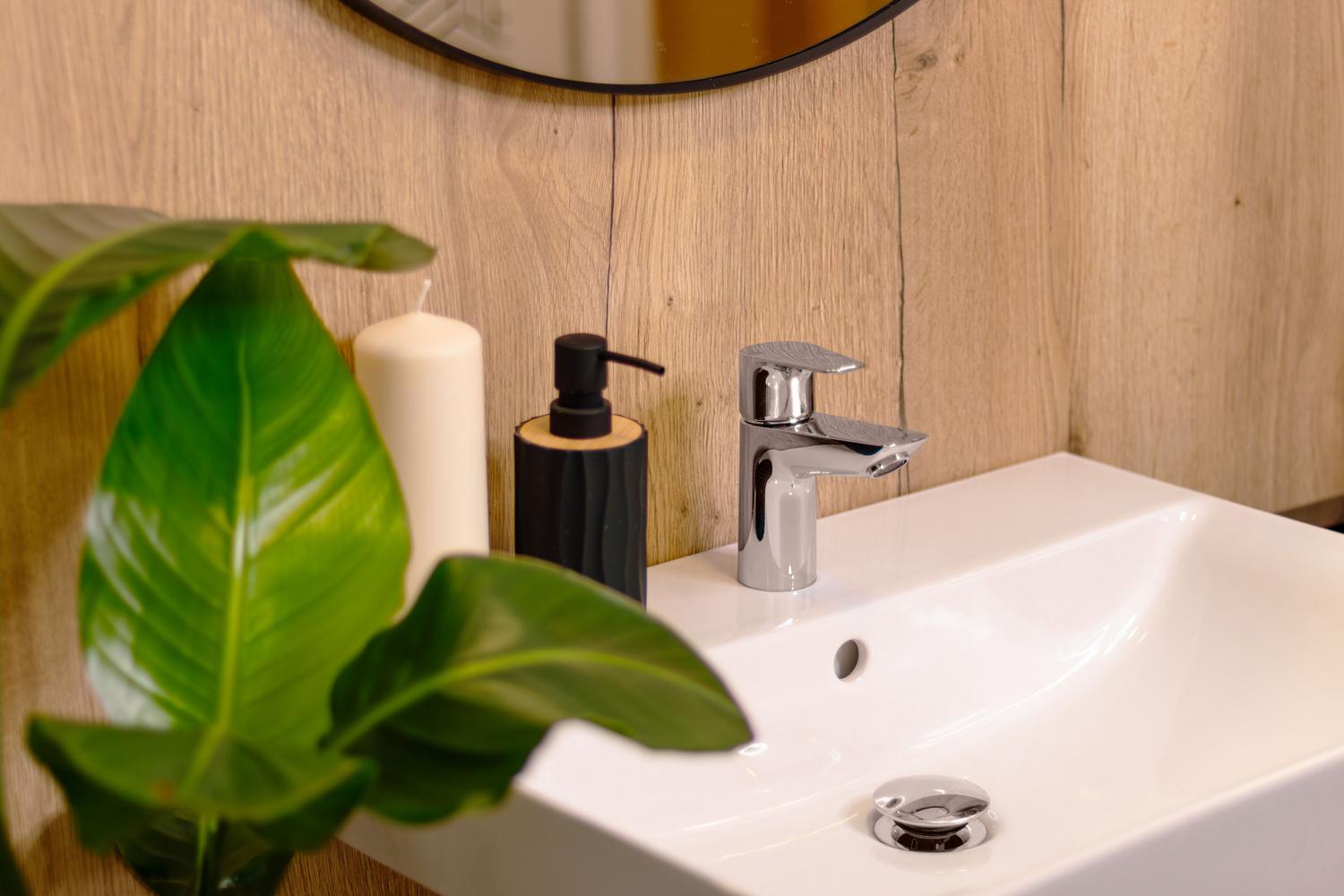 Lavabo moderno con grifo monomando y decoración natural con plantas, evocando sostenibilidad y frescura.