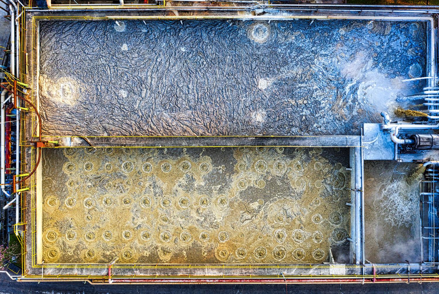 Detalle aéreo de tanques de aireación en una planta de tratamiento de aguas residuales, donde se produce la oxigenación de los lodos activados.