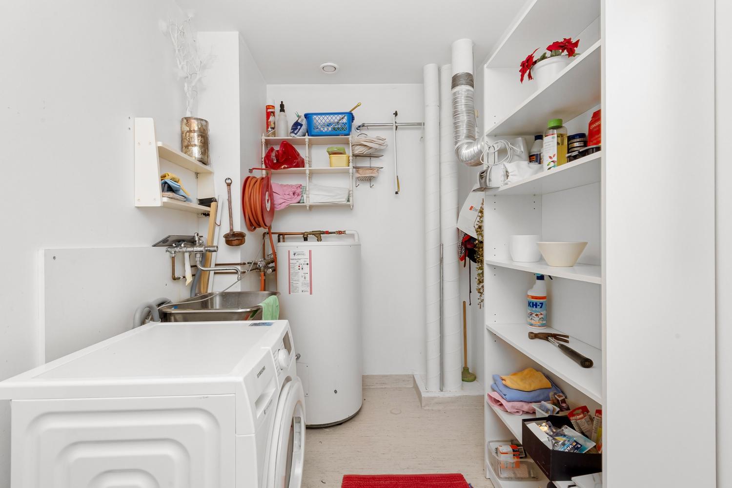 Cuarto de lavado doméstico organizado con un acumulador de agua caliente integrado.