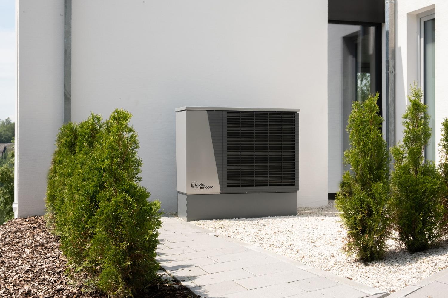 Bomba de calor aerotermia instalada en un entorno residencial moderno rodeada de vegetación. Bomba de calor aerotermia instalada en un entorno residencial moderno rodeada de vegetación.