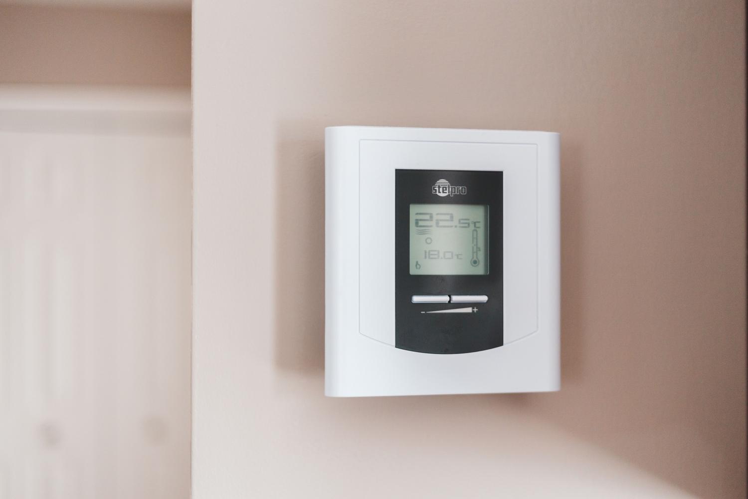Termostato digital moderno instalado en una pared para el control eficiente de la climatización del hogar.