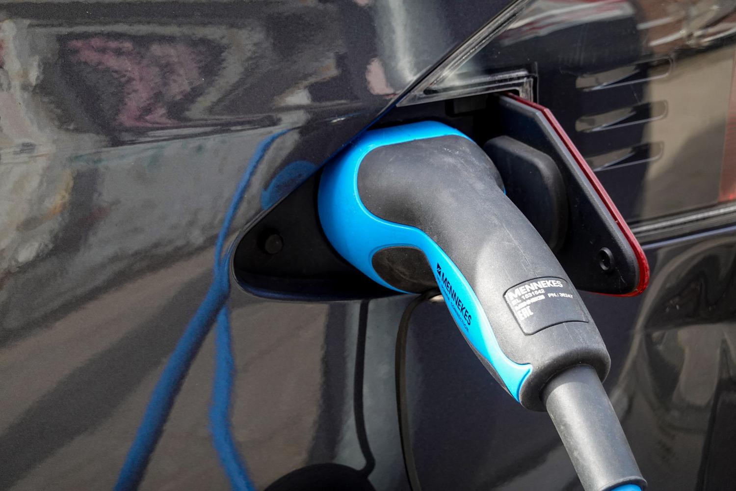 Primer plano detallado de un conector de carga Mennekes enchufado en un coche eléctrico.