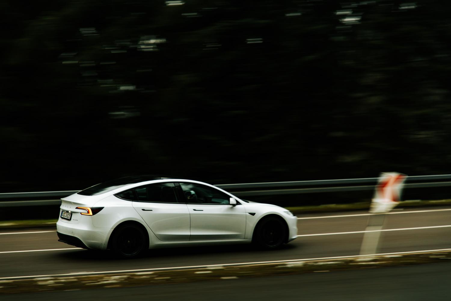 Tesla Model 3 circulando a alta velocidad por una autopista, simbolizando la eficiencia en viajes largos.