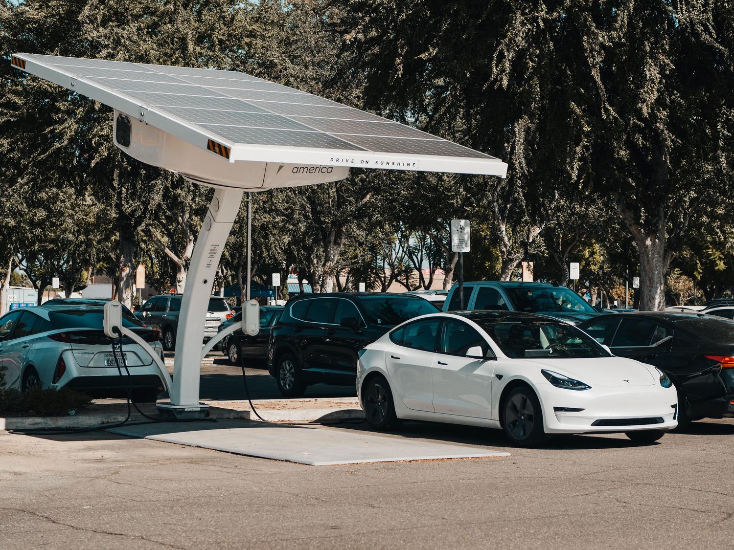 Estación de carga para coches eléctricos alimentada por paneles solares con el lema 'Drive on Sunshine'.
