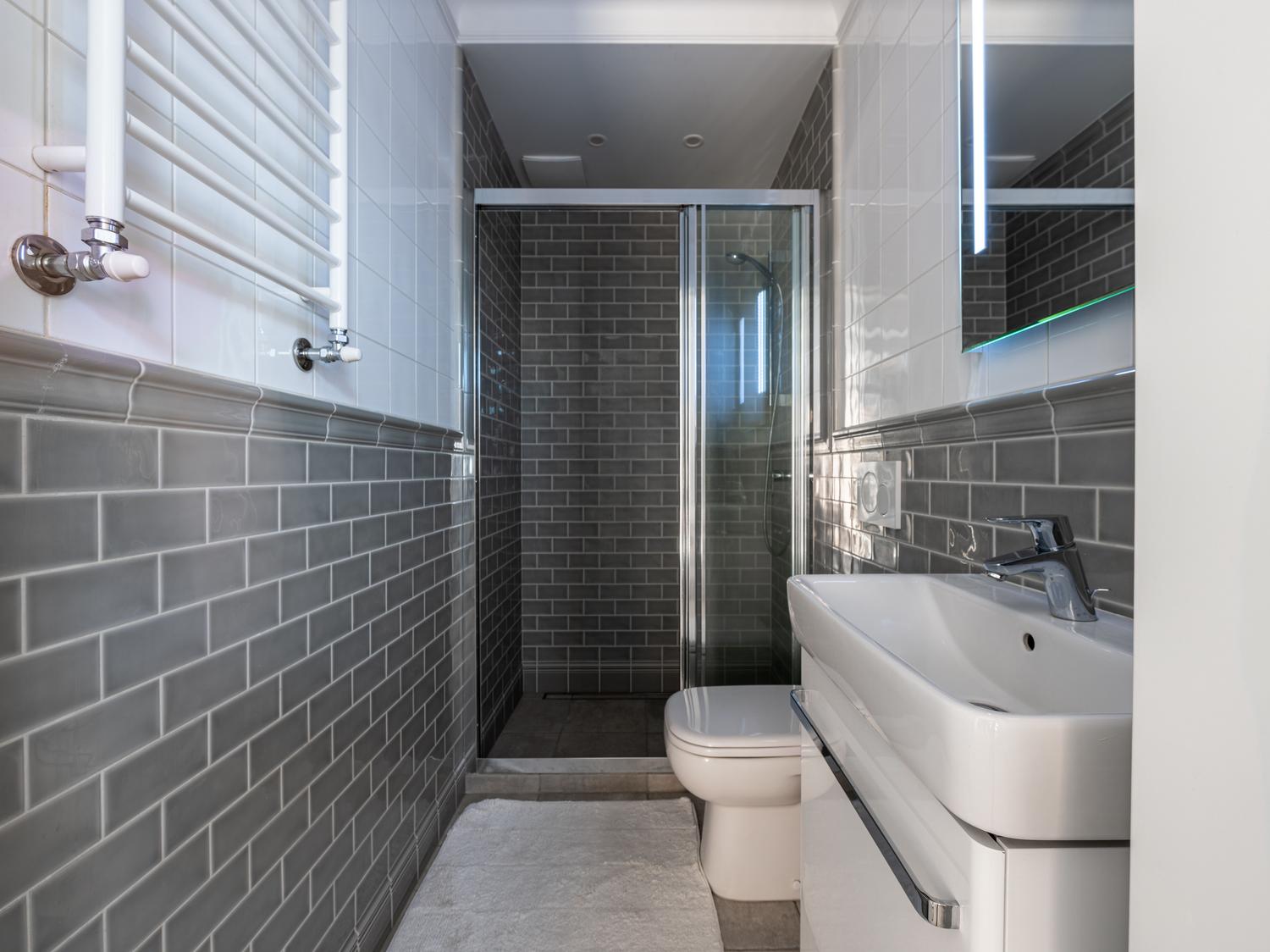 Baño moderno con azulejos tipo metro en color gris, ideal como ejemplo de revestimiento contemporáneo.