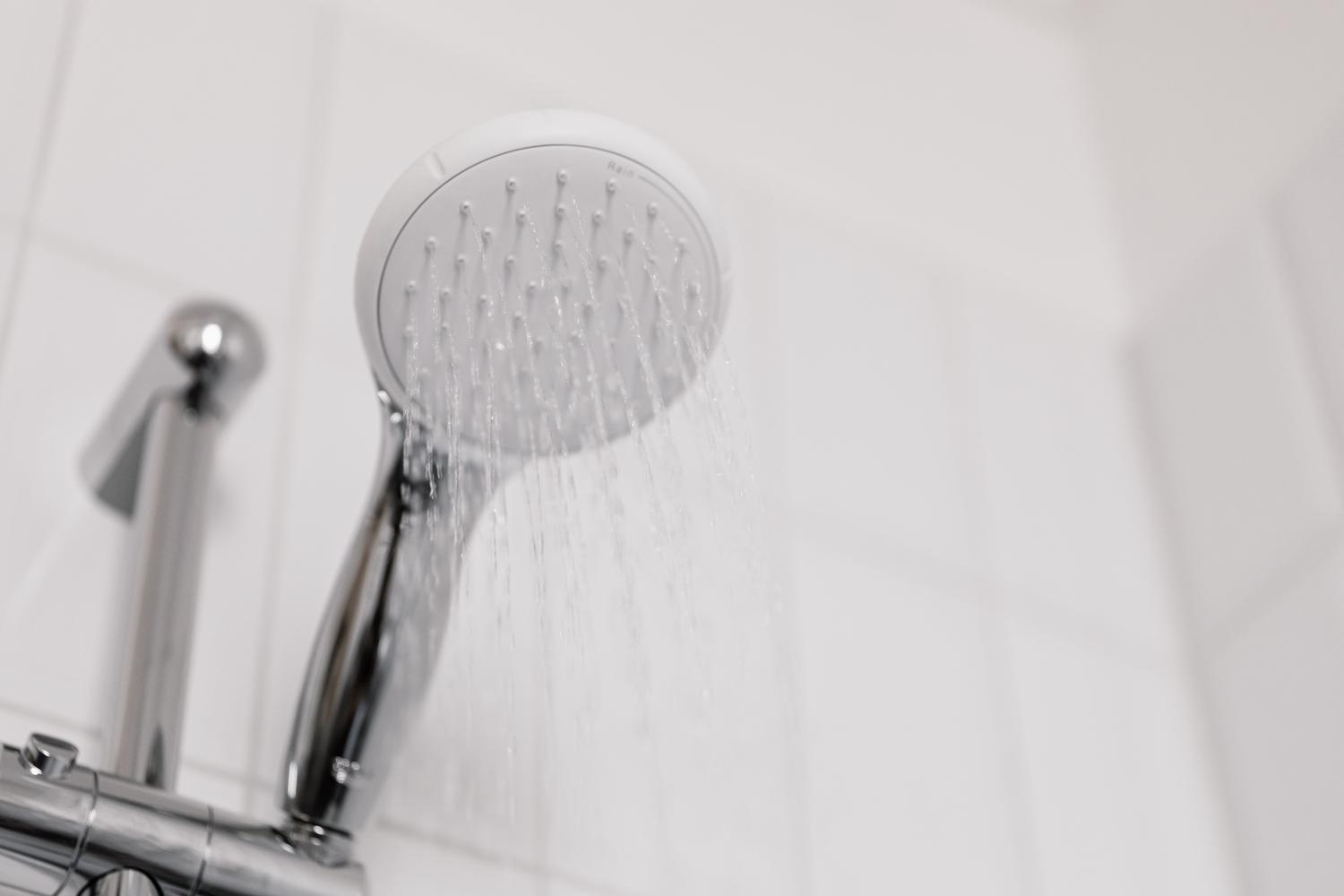 Primer plano de un cabezal de ducha eficiente con flujo de agua, ideal para el ahorro de agua caliente.