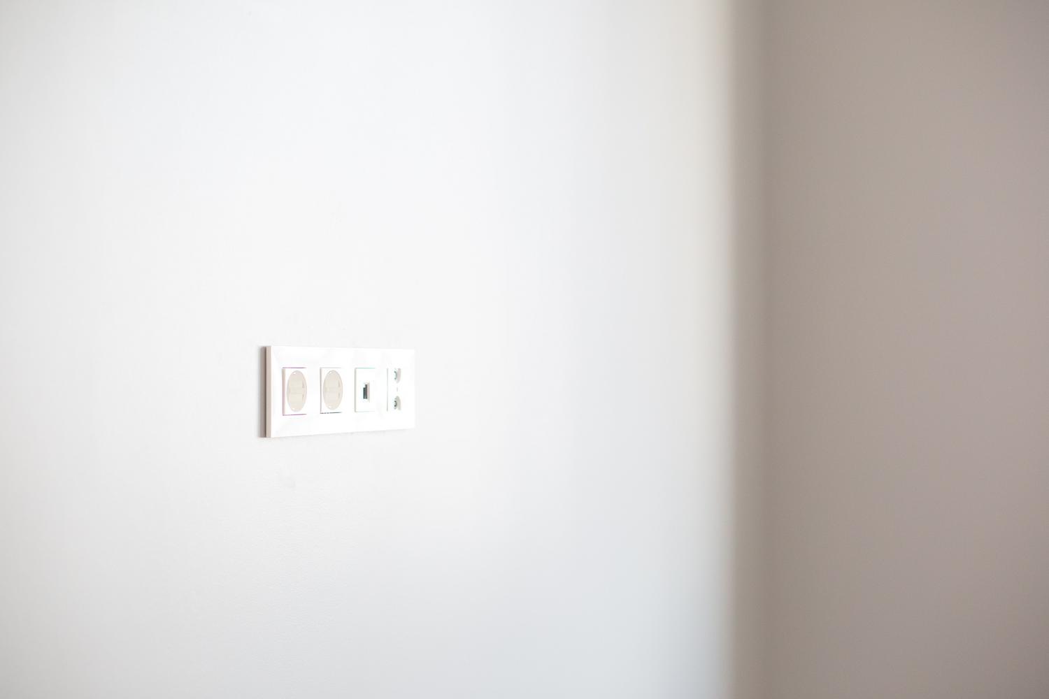 Primer plano de un enchufe eléctrico moderno en una pared blanca, simbolizando el suministro y la potencia contratada en el hogar.