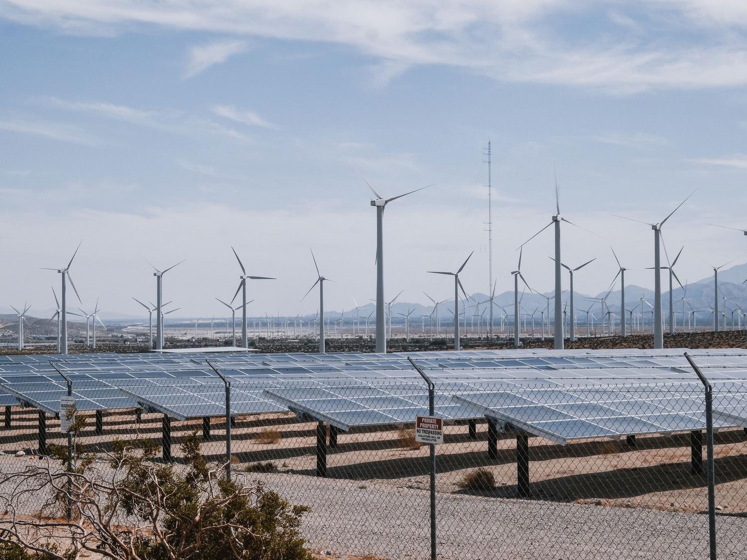 Parque de energía renovable con aerogeneradores y paneles solares bajo un cielo despejado, representando los cargos para el fomento de energías limpias. Parque de energía renovable con aerogeneradores y paneles solares bajo un cielo despejado, representando los cargos para el fomento de energías limpias.