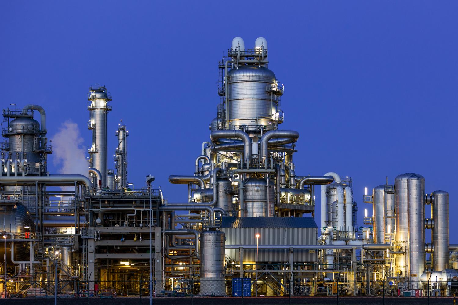 Refinería química moderna iluminada al atardecer, resaltando la tecnología avanzada.