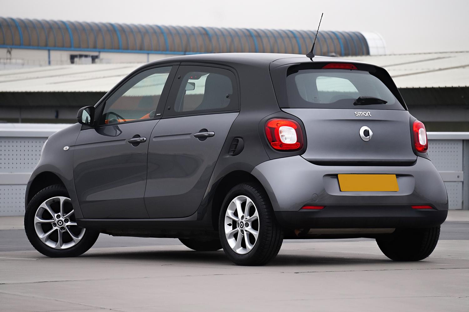 Coche Smart ForFour gris en entorno urbano, ideal para el ahorro en ciudad