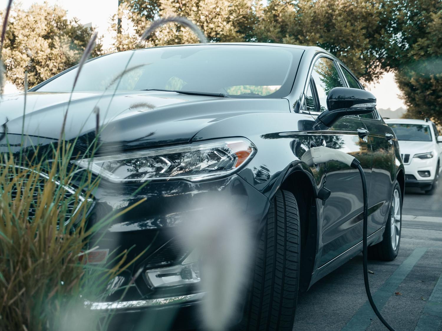 Coche híbrido enchufable cargando su batería en una estación eléctrica