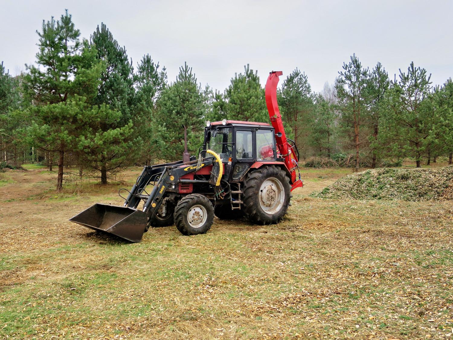 Tractor equipado con astilladora forestal procesando madera en el bosque. Tractor equipado con astilladora forestal procesando madera en el bosque.