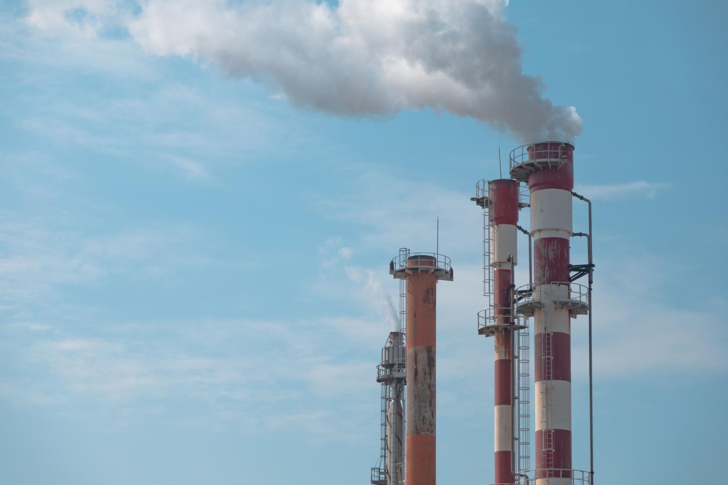 Chimeneas industriales liberando emisiones gaseosas al aire, representando la contaminación atmosférica.
