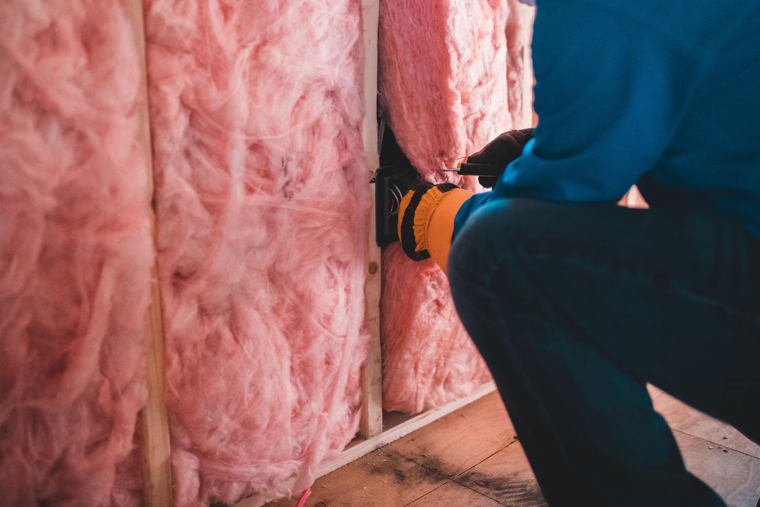 Trabajador instalando aislamiento térmico en una vivienda, ilustrando los procesos de rehabilitación energética necesarios para mejorar el CEE.