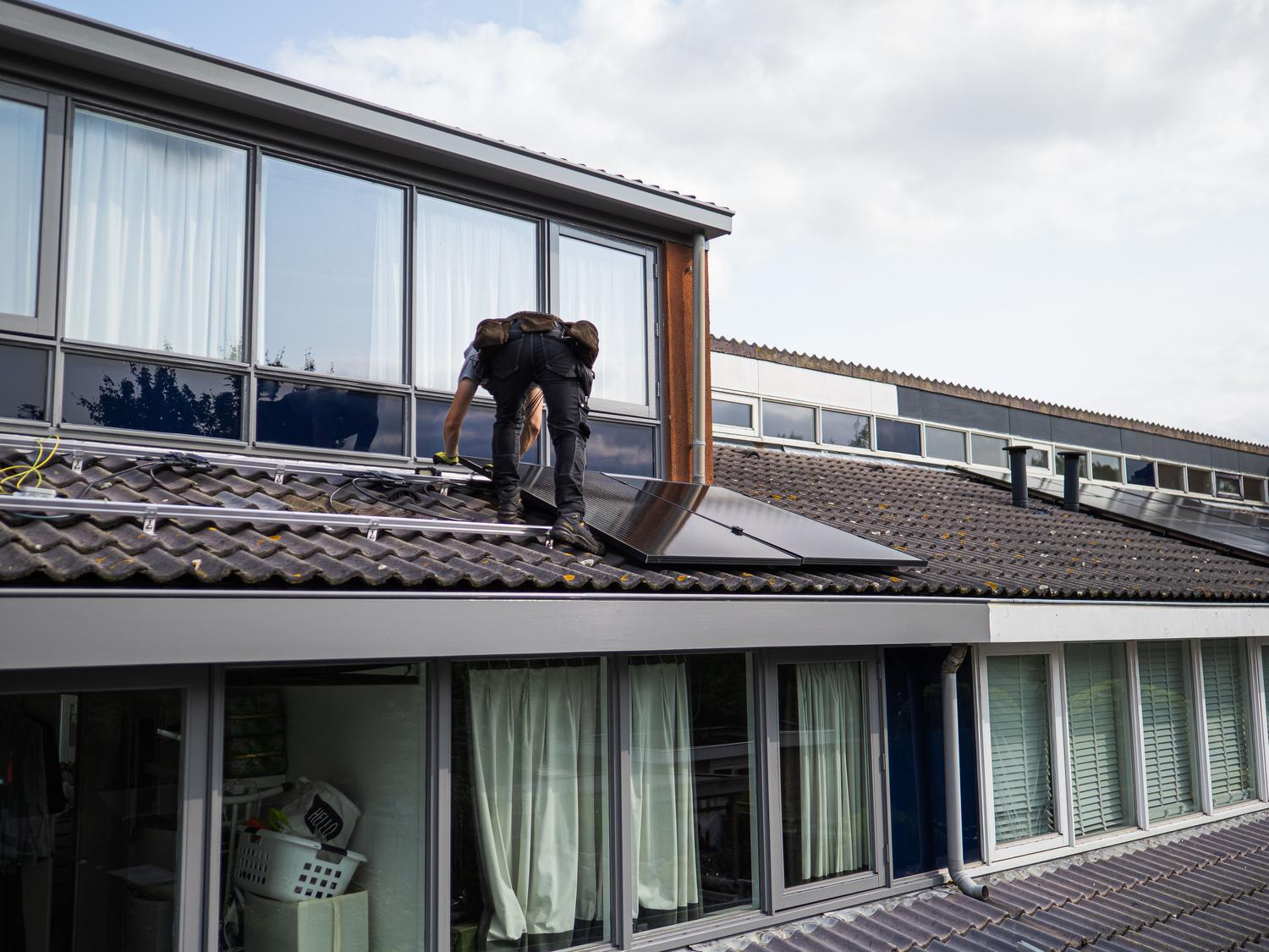 Técnico profesional instalando paneles solares en el tejado de una vivienda para asegurar el máximo rendimiento.