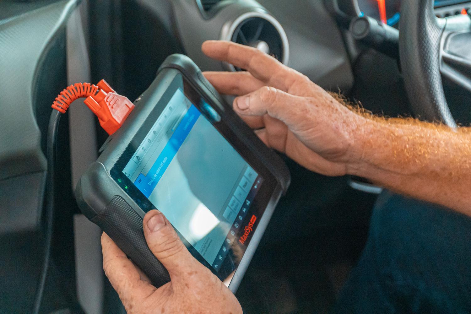 Mecánico utilizando una tableta de diagnóstico avanzado para configurar sistemas electrónicos de un vehículo eléctrico.