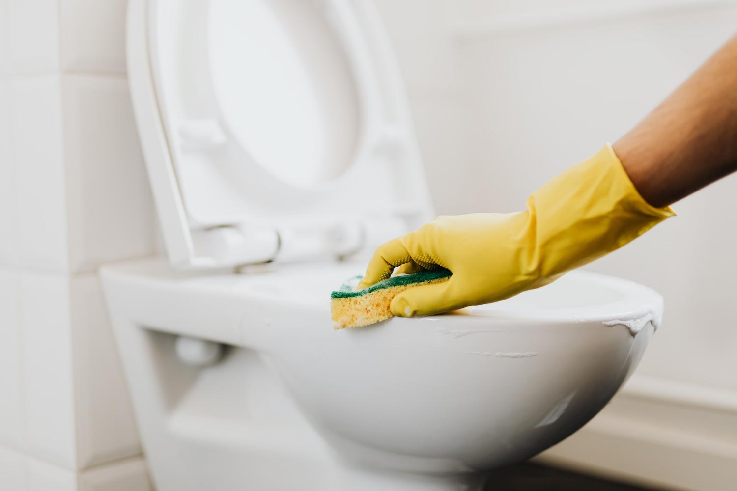 Limpieza del borde del inodoro con una esponja y detergente.