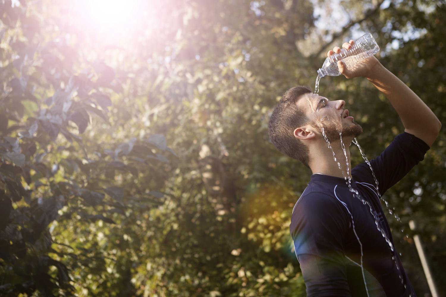 Hombre refrescando su rostro con agua fresca para bajar la temperatura corporal durante un día caluroso.