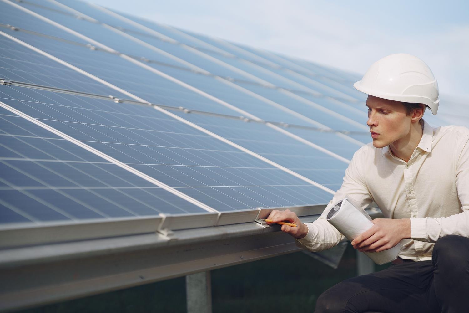 Técnico especializado revisando los módulos de una estación de control e inversores en una planta fotovoltaica.