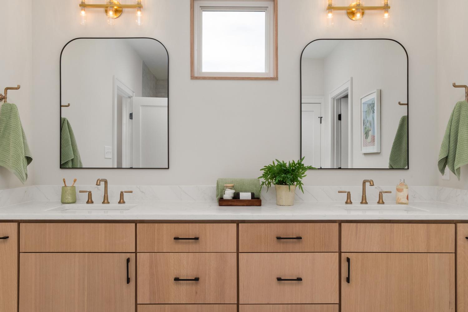 Lavabo doble moderno con grifería en tono dorado cepillado y encimera de mármol, mostrando armonía decorativa.