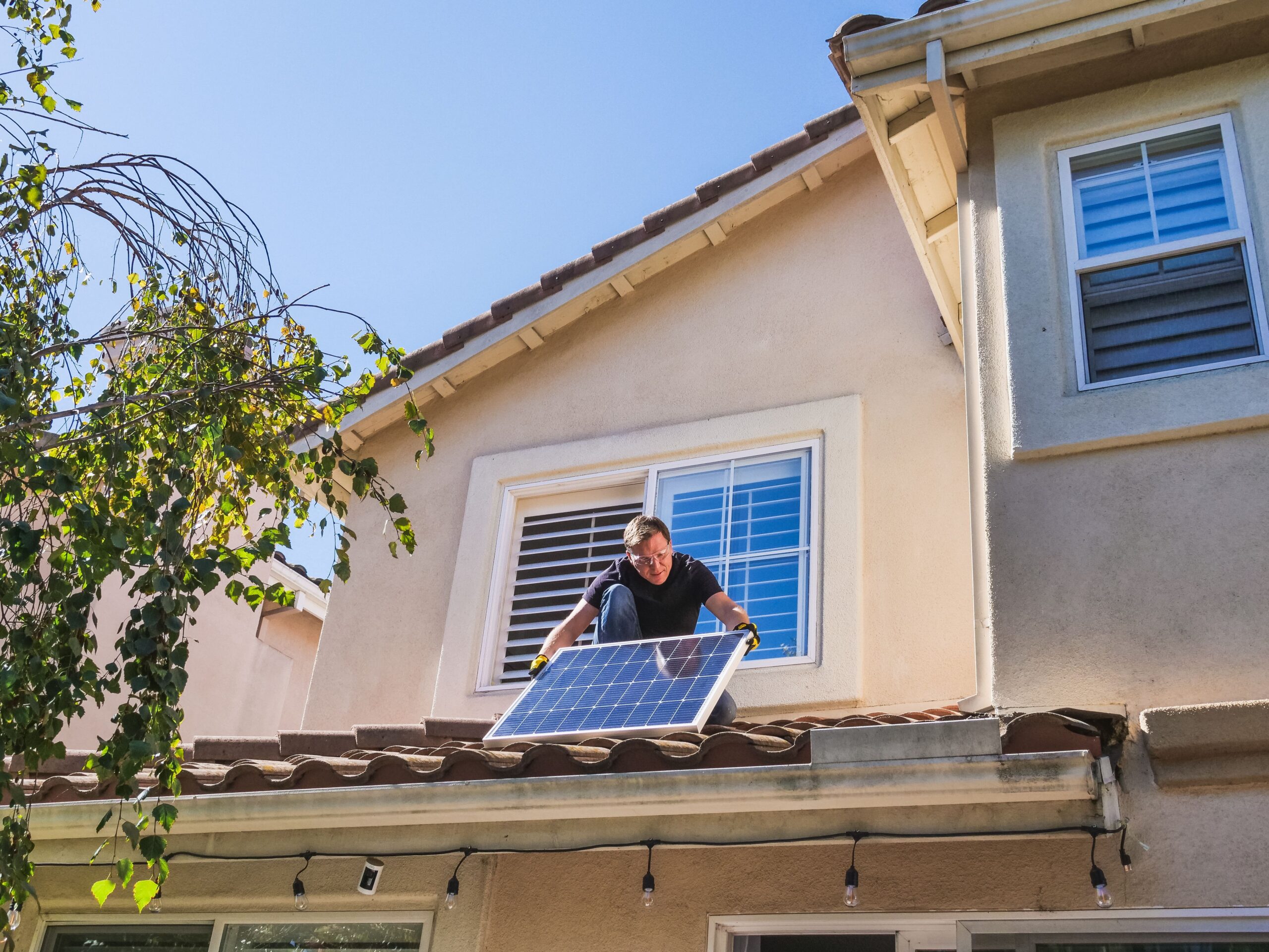 Técnico instalando un panel solar fotovoltaico en el tejado de una vivienda unifamiliar, representando la inversión inicial en energía renovable.