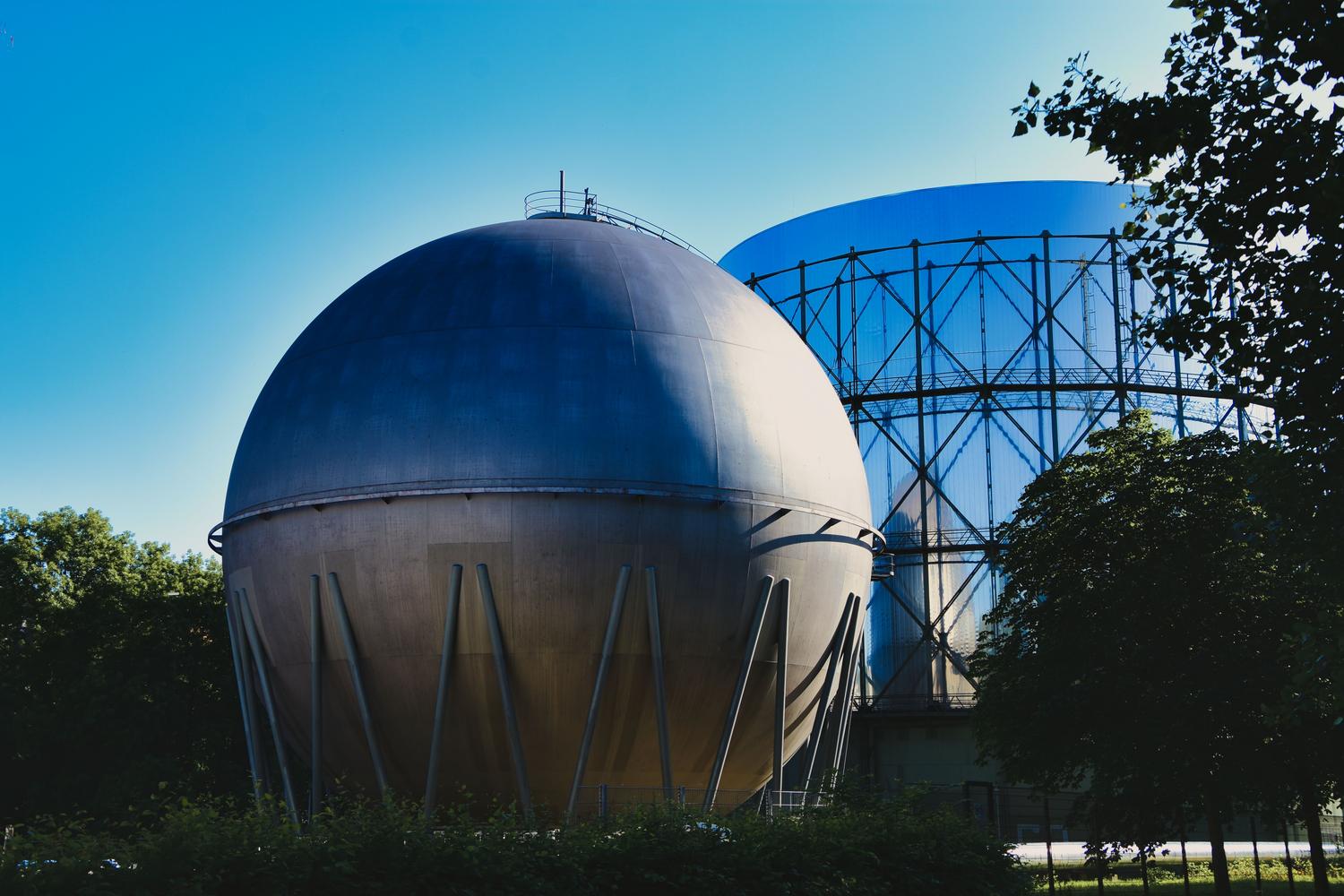 Gasómetros industriales bajo un cielo despejado, representando la infraestructura de almacenamiento de gas.