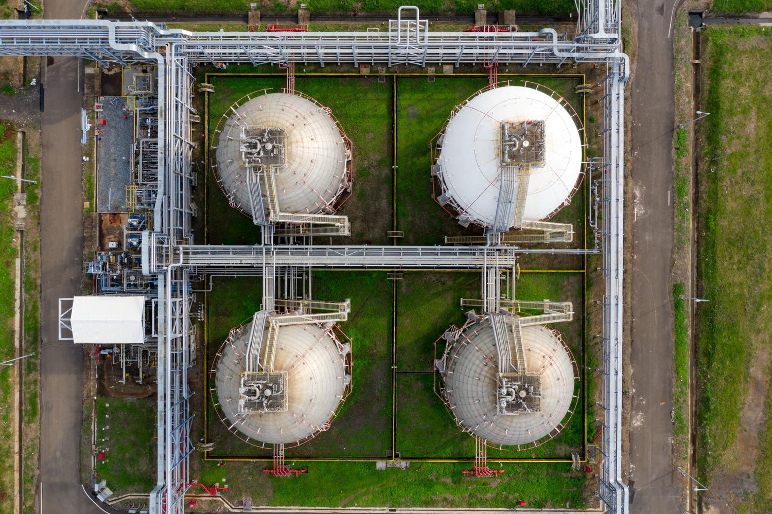 Detalle aéreo de tanques de almacenamiento y tuberías industriales, reflejando los activos físicos de una inversión en biometano.