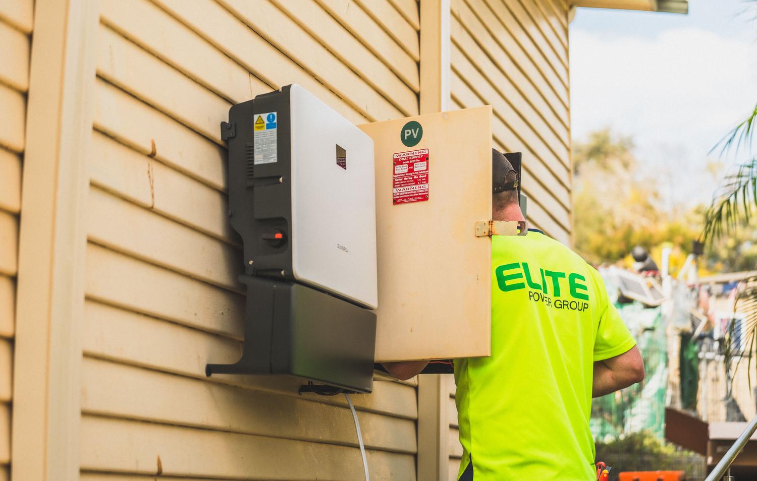 Técnico instalando un inversor de gestión de batería solar en el exterior de una vivienda. Técnico instalando un inversor de gestión de batería solar en el exterior de una vivienda.
