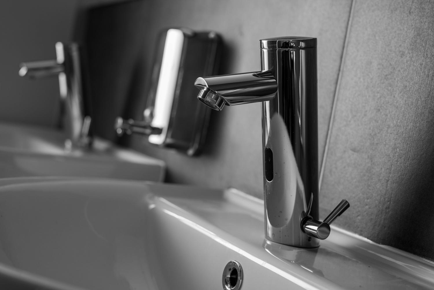Grifo electrónico moderno de acero inoxidable en un baño minimalista.