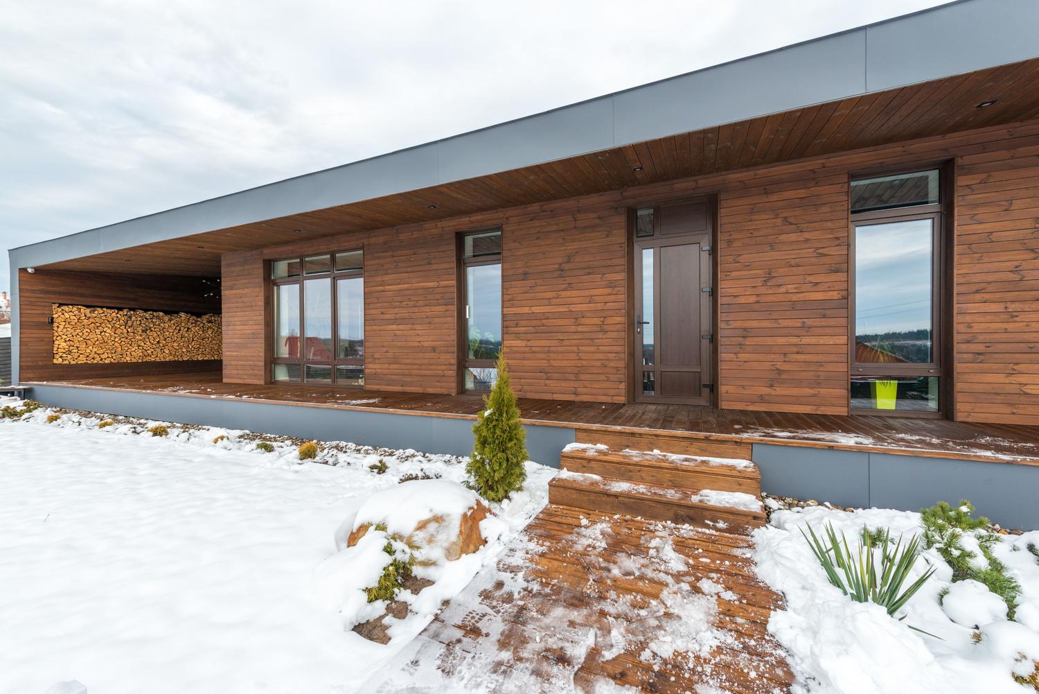 Casa moderna de madera en un entorno invernal nevado.