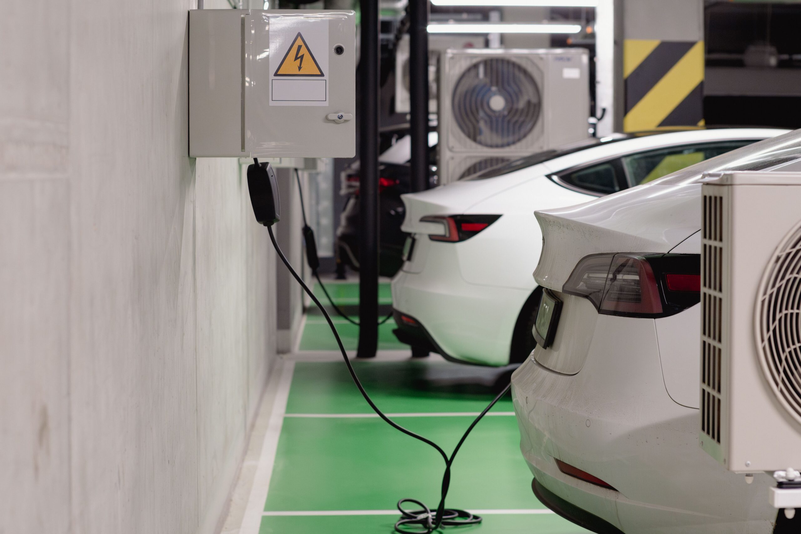 Vehículos eléctricos cargando en un parking subterráneo moderno, mostrando la infraestructura de carga urbana.