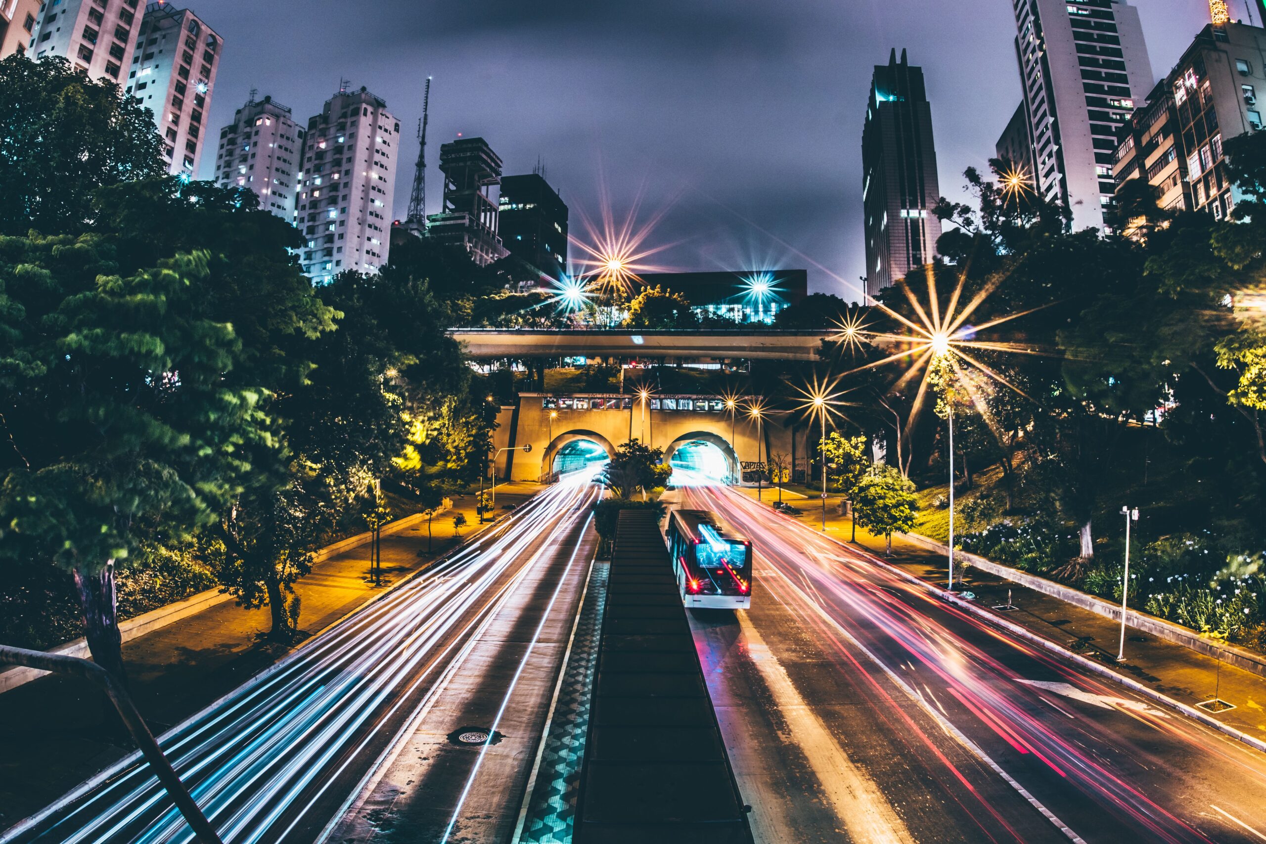 Fotografía de larga exposición de una autopista urbana nocturna con estelas de luz, simbolizando el flujo de datos y la conectividad de los ITS.