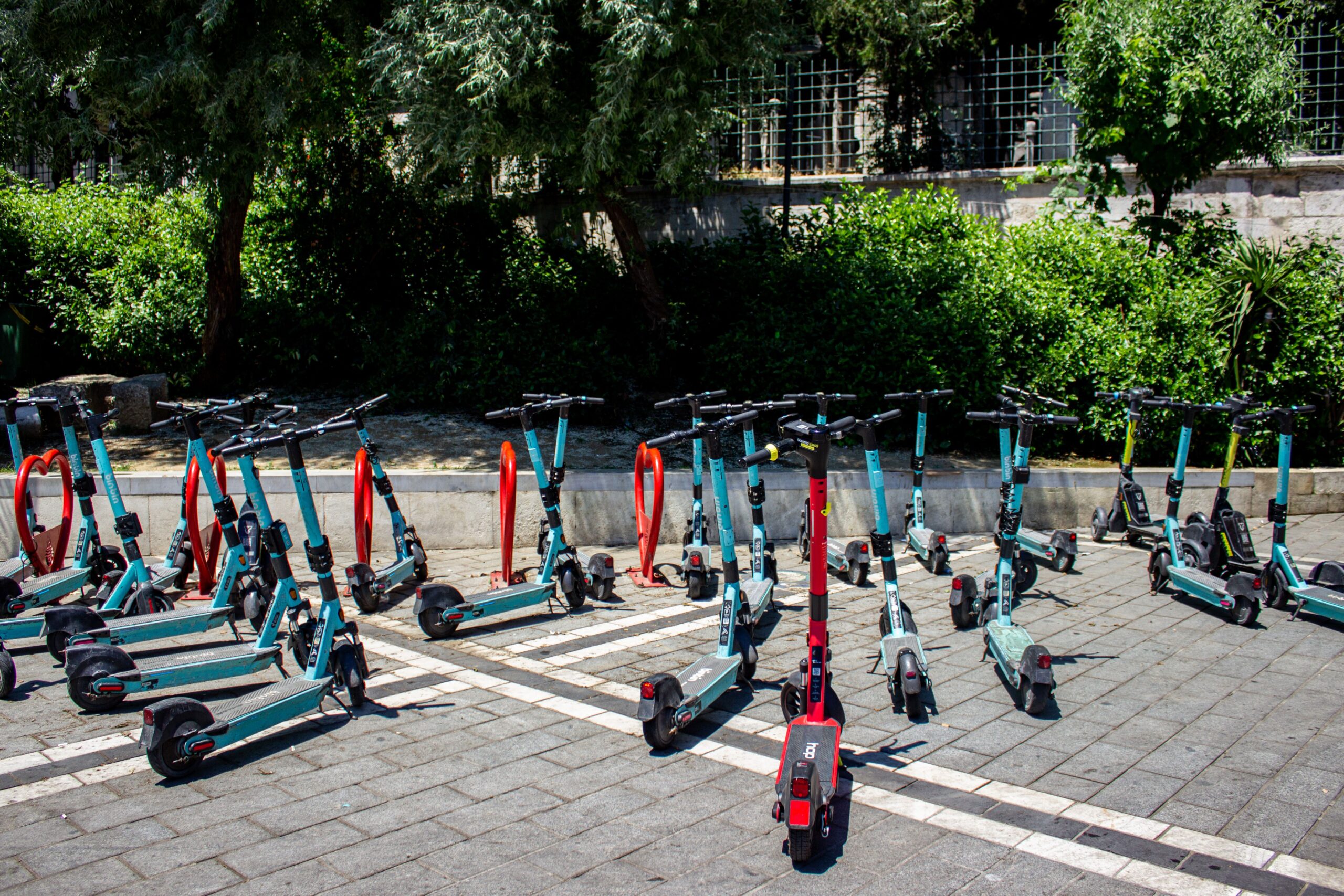 Fila de patinetes eléctricos compartidos estacionados en una zona urbana, ejemplificando la micromovilidad y el transporte flexible.