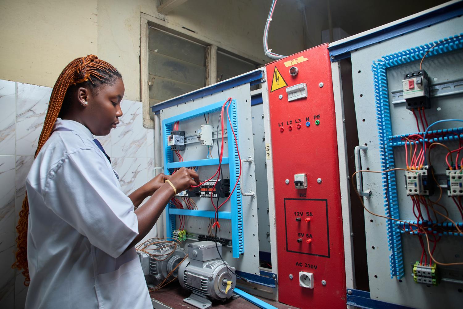 Técnica especializada realizando el mantenimiento de un panel de control eléctrico industrial.