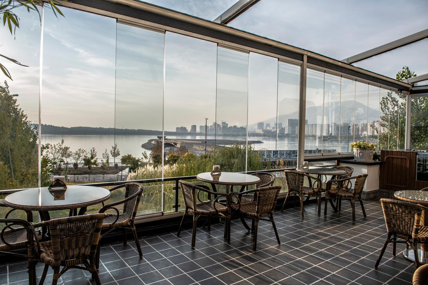 Terraza moderna con cerramiento de cristal panorámico que ofrece vistas a la ciudad y el lago