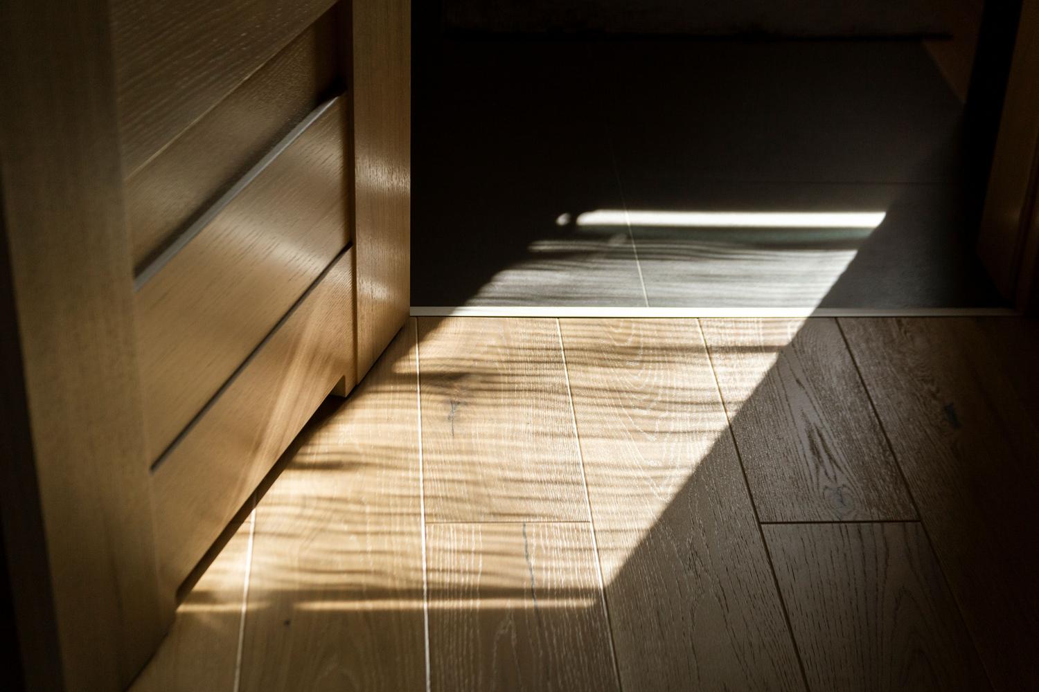 Detalle de suelo de parquet con luz natural, resaltando la calidez y la estética atemporal de la madera natural.