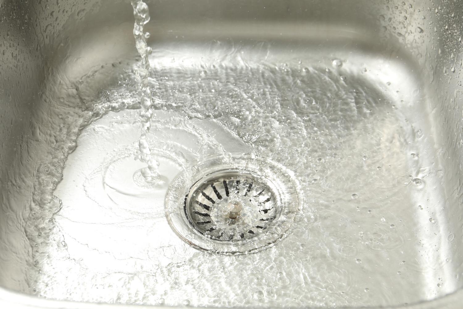 Primer plano de agua bajando por el desagüe de un fregadero de cocina