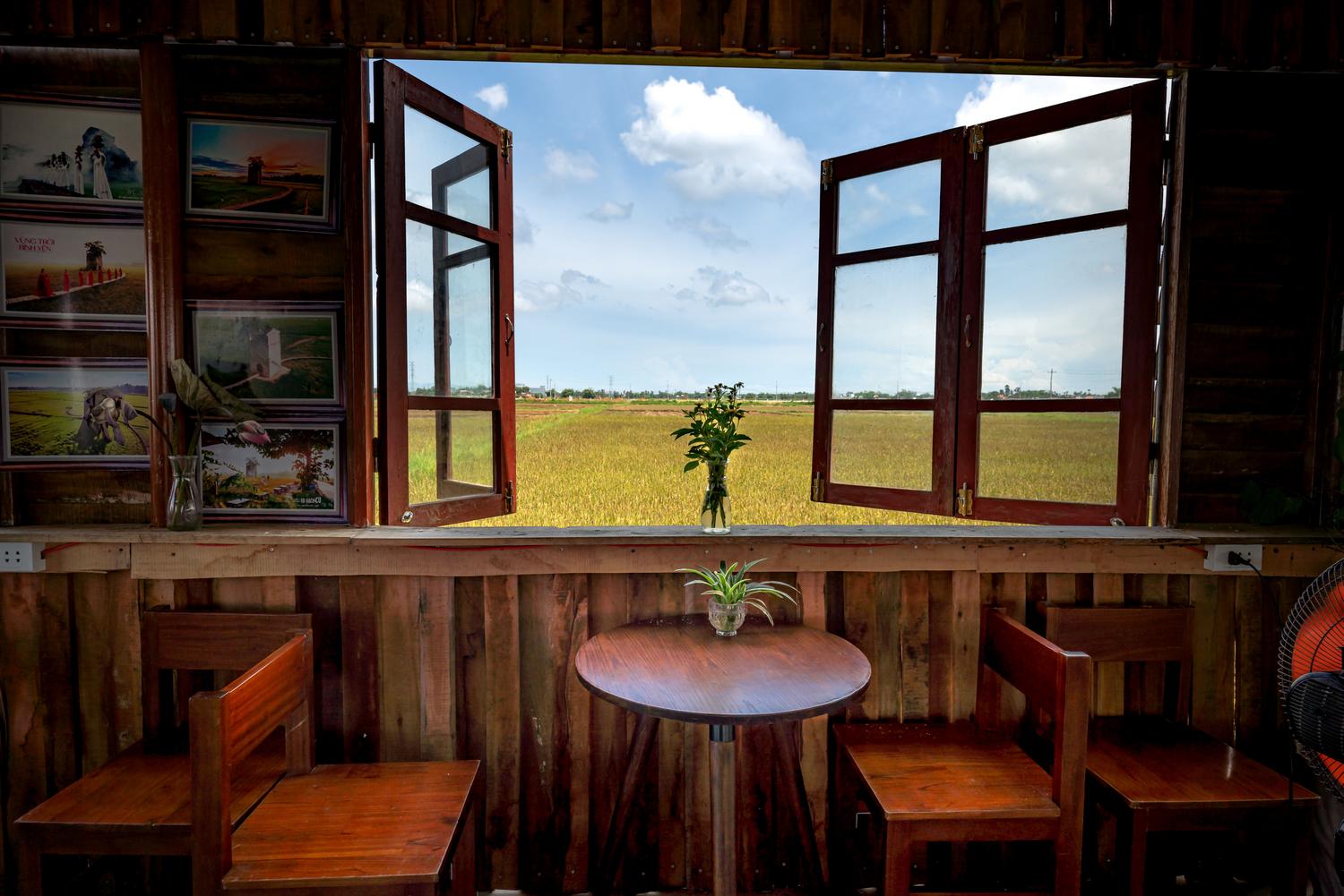 Habitación rústica con ventanas abiertas que permiten la entrada de aire fresco y vistas a un campo tranquilo.